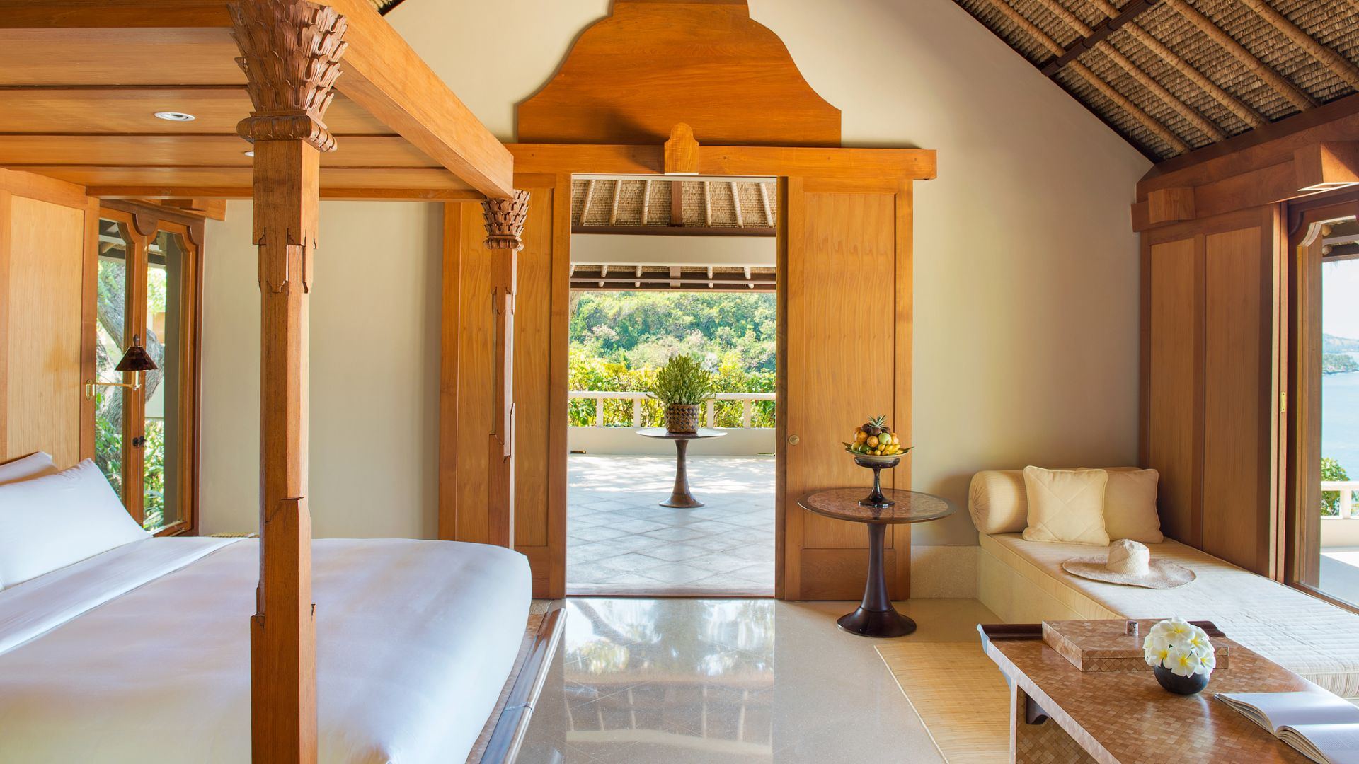 Interior of a suite bedroom at Amankila, with a four-poster bed and a view through to the terrace