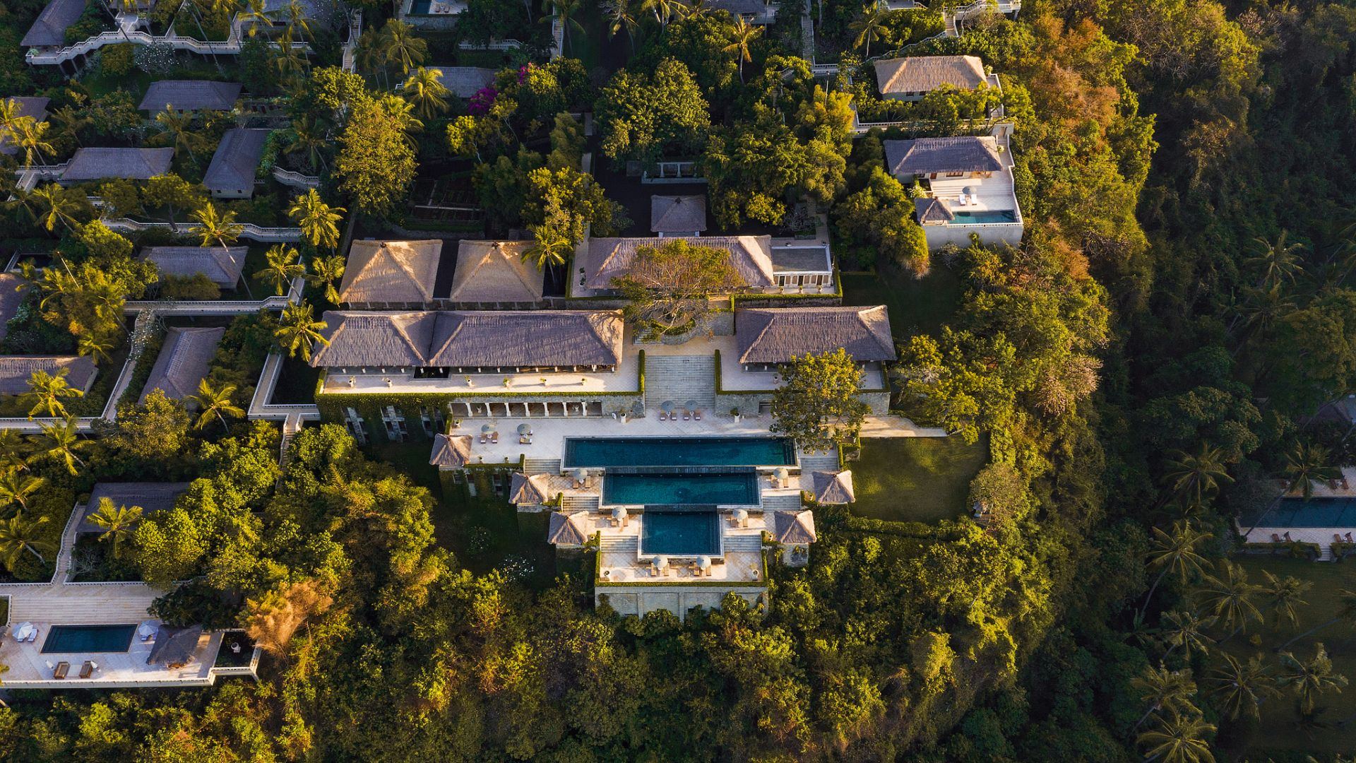 Aerial view of Amankila's three-tier pool and grounds, framed by jungle