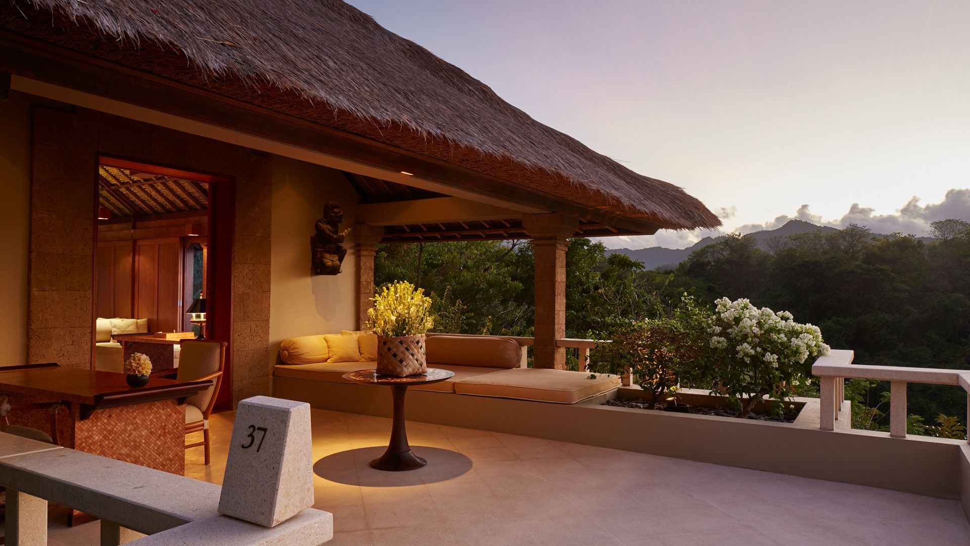 A suite terrace at Amankila at dusk, with a daybed and views over the jungle
