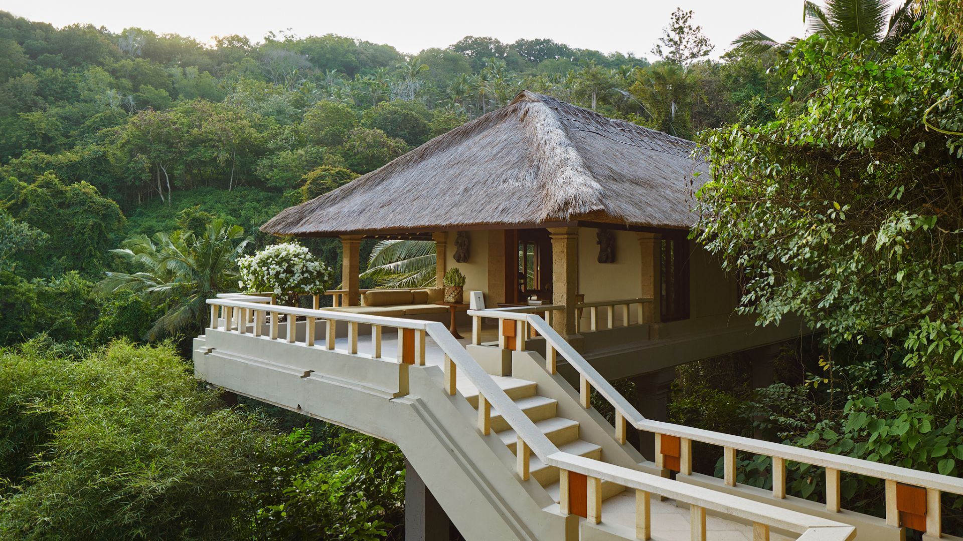Raised timber walkway leading to a thatched-roof suite through the jungle at Amankila