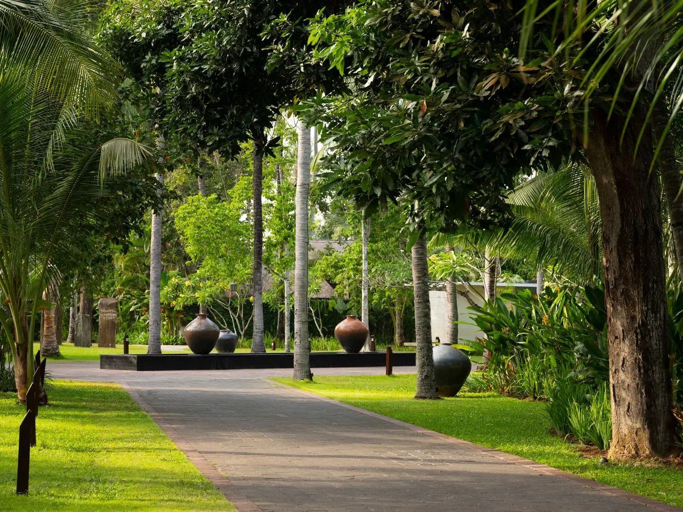 A garden path lined with palms and traditional urns leading through Kayumanis Jimbaran