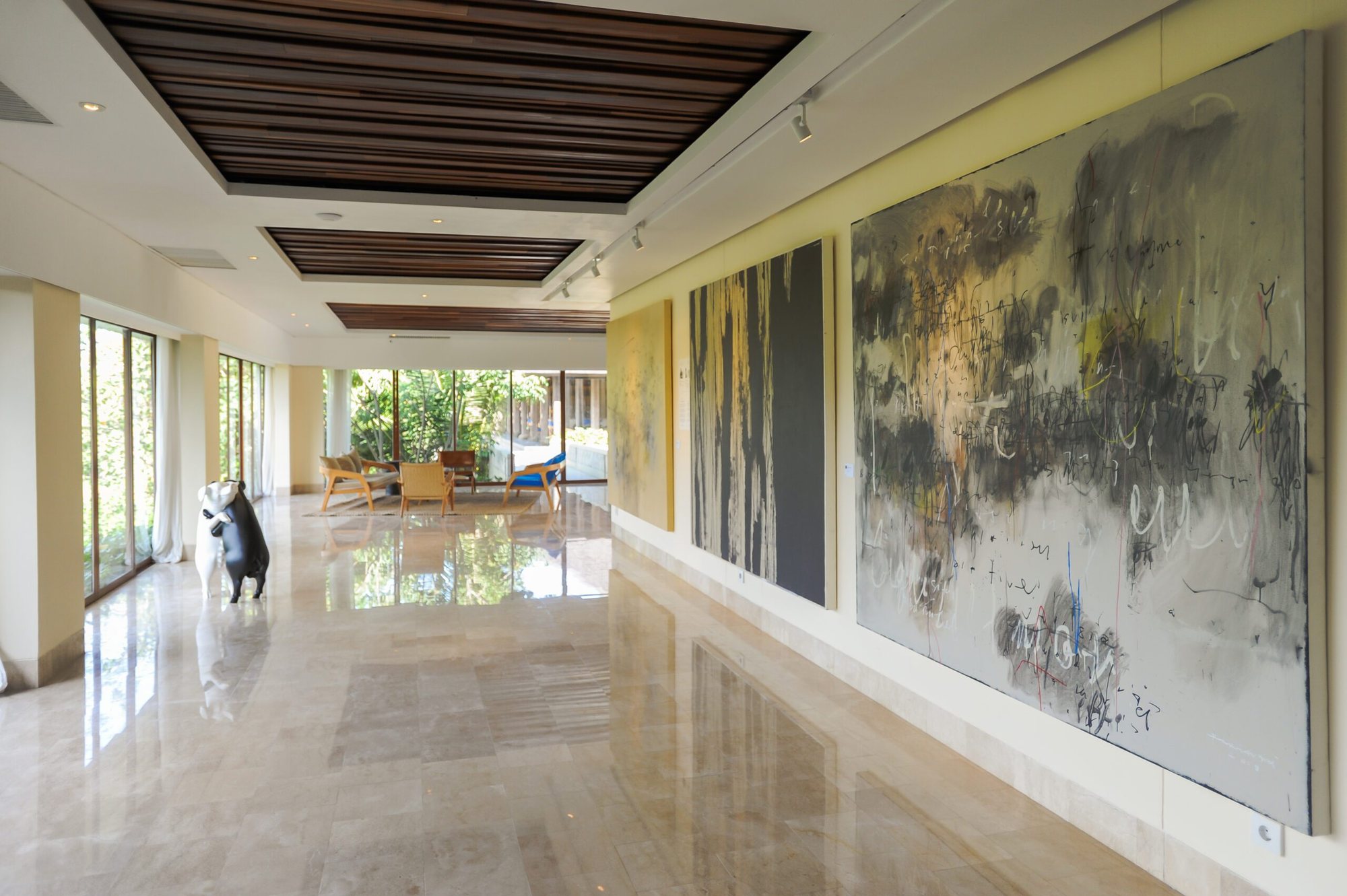 Gallery hallway at Komaneka at Keramas Beach lined with large contemporary Indonesian paintings
