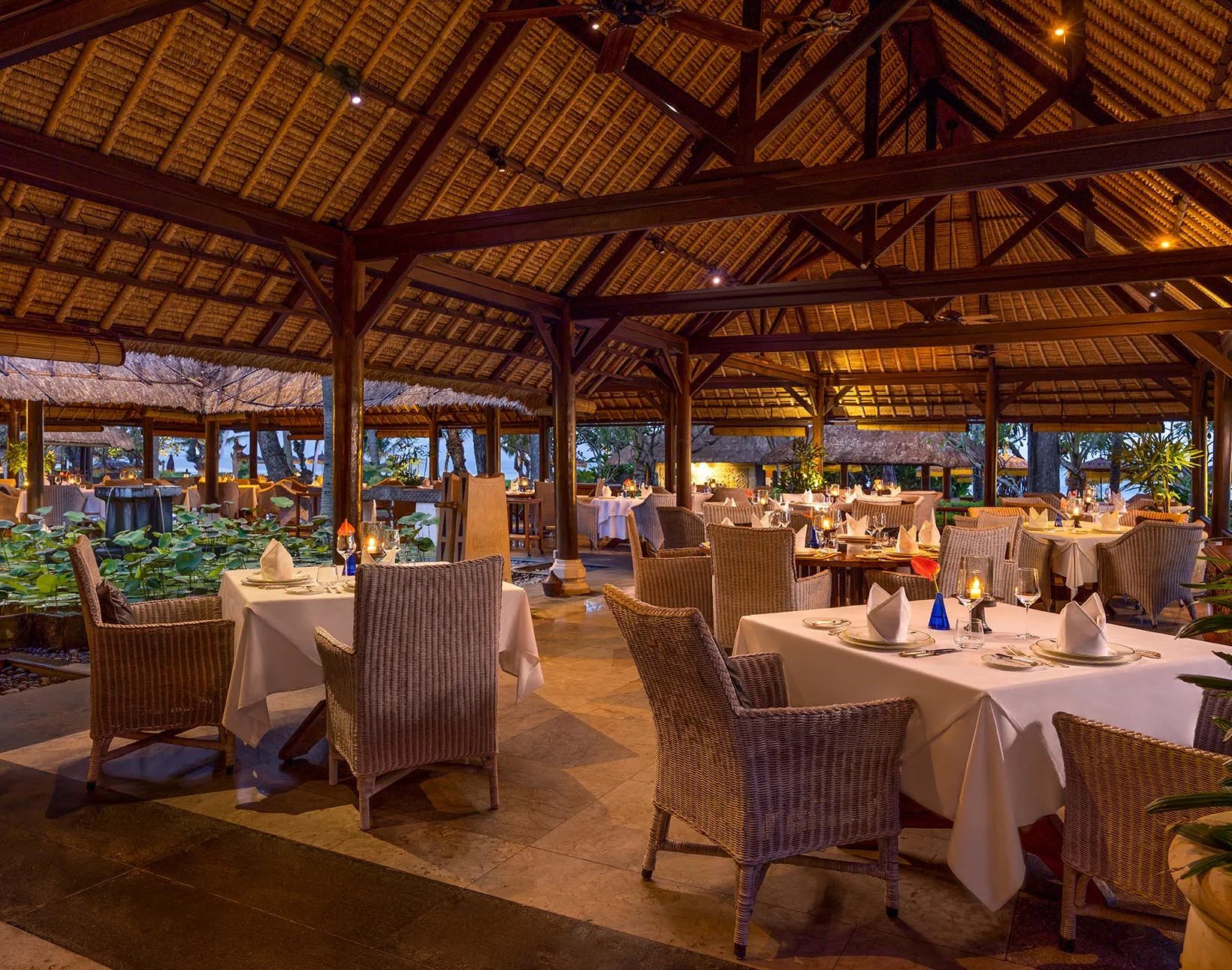 Open-air restaurant beside a lily pond at The Oberoi Bali, set for dinner in the evening